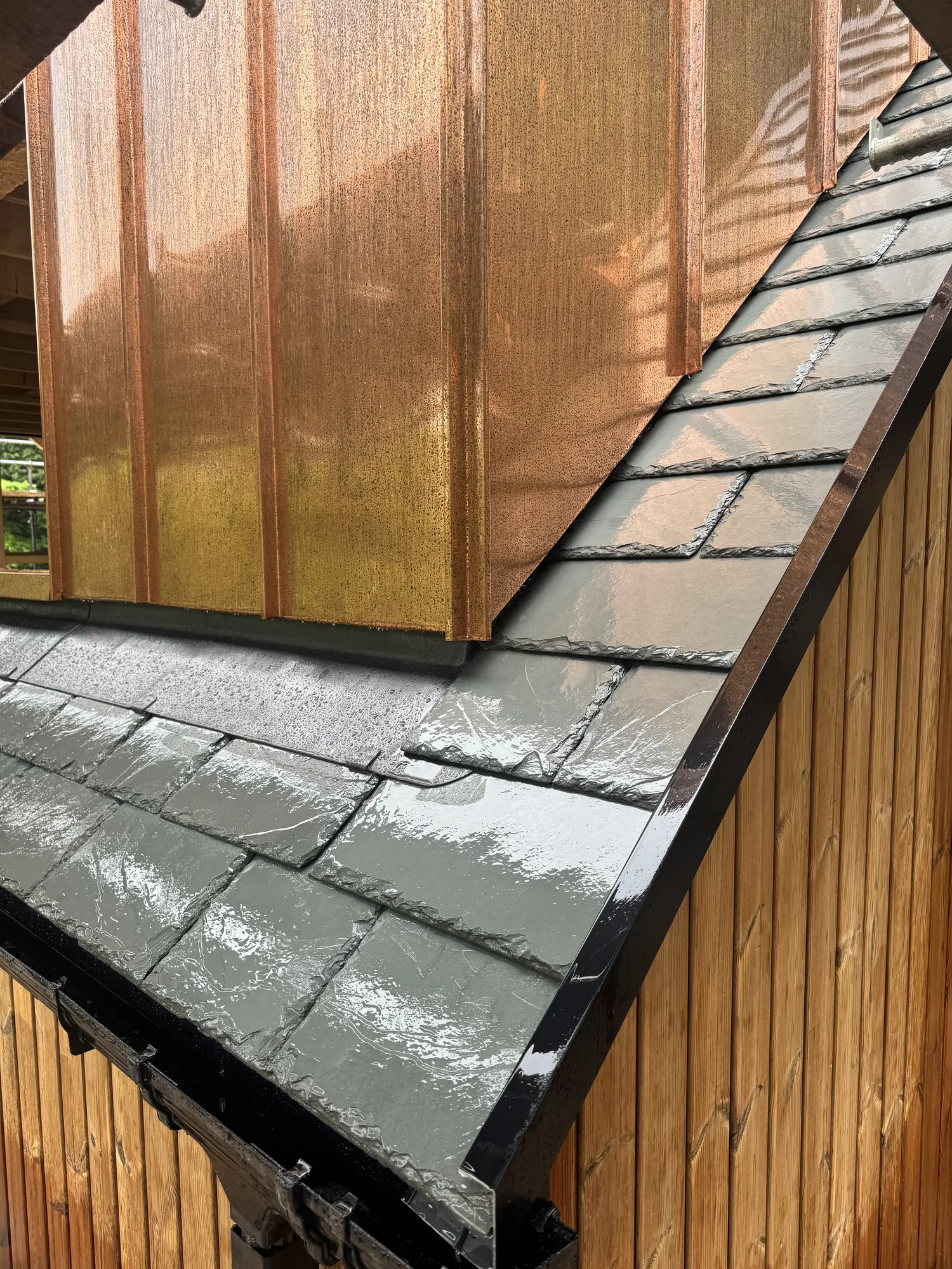 Random-width natural slate roof with copper dormers on a bespoke new build