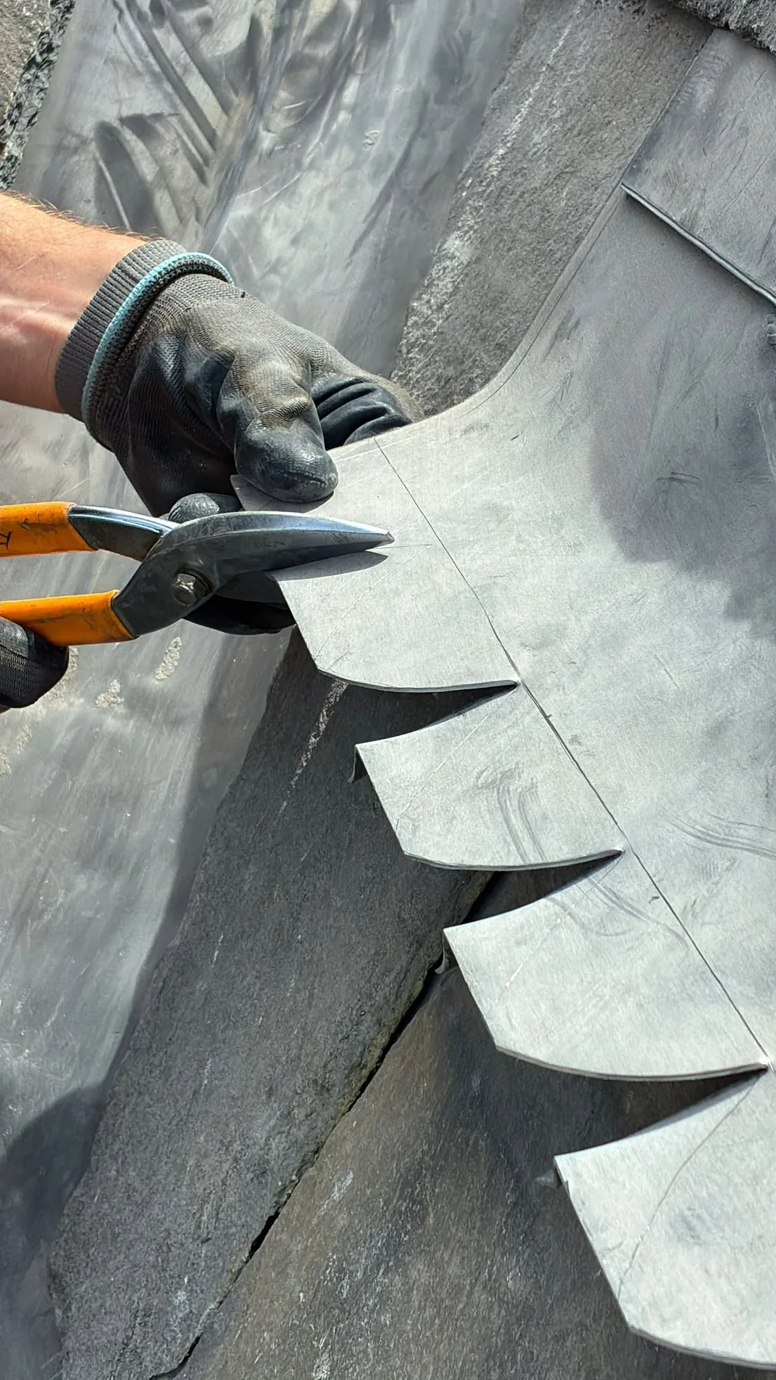 Hand-cutting a decorative scalloped lead detail on site