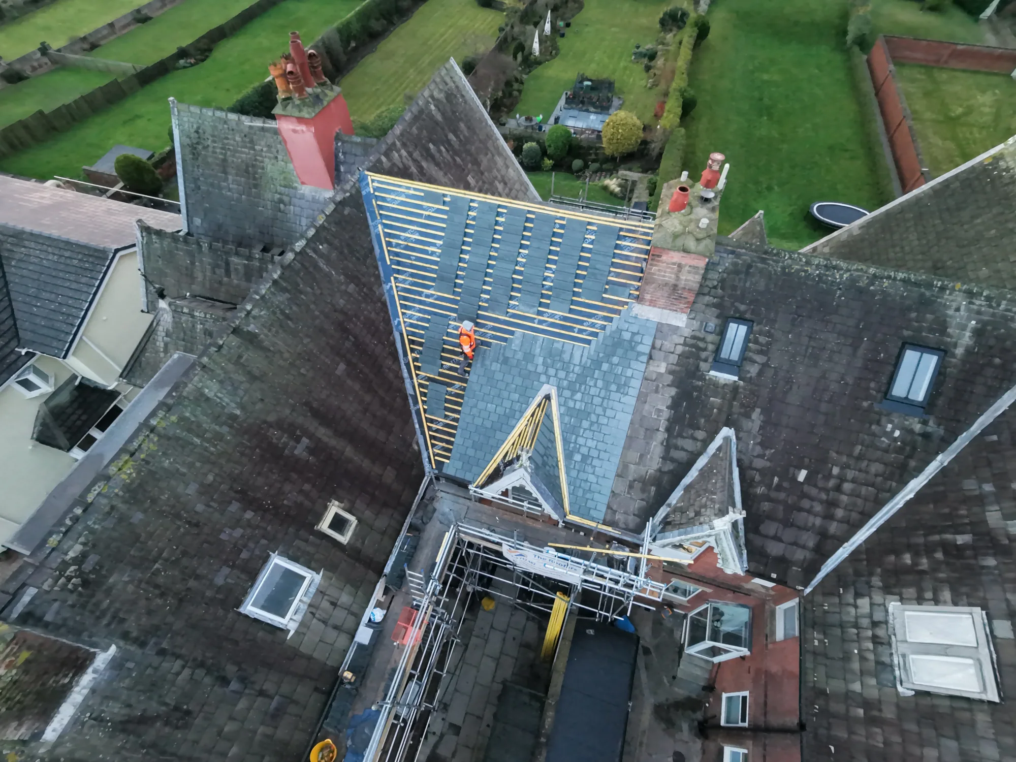 Steep slate re-roof in progress with a chimney